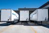 Cargo trailers parked at an industrial shipping dock under clear blue skies