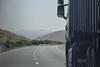 Truck on a winding highway in Douar Ouled El Mesnaoui, Morocco, set in a rocky landscape.