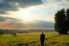women look at sunny clouds in field