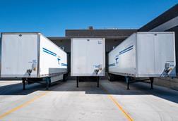 Cargo trailers parked at an industrial shipping dock under clear blue skies