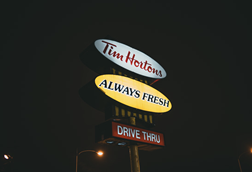Illuminated Tim Hortons drive-thru sign glowing against a dark night sky