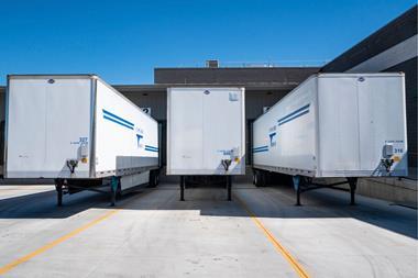 Cargo trailers parked at an industrial shipping dock under clear blue skies