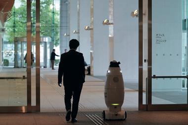 Office worker in Tokyo walks alongside a security robot
