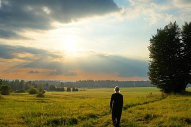 women look at sunny clouds in field