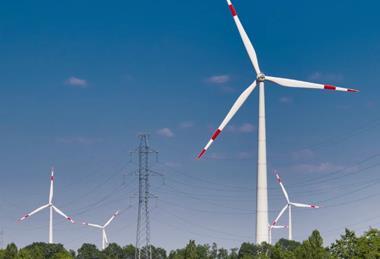 Wind turbines generating energy alongside power lines