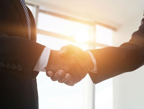 dealmakers handshake with sun coming through windowrs